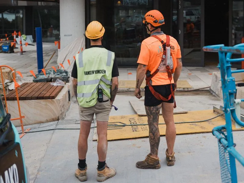 Two hi-vis construction workers surveying a newly built commercial building on site